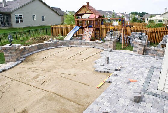 a backyard that has been half paved with stacks of pavers ready to be laid down around it by paving Ballarat